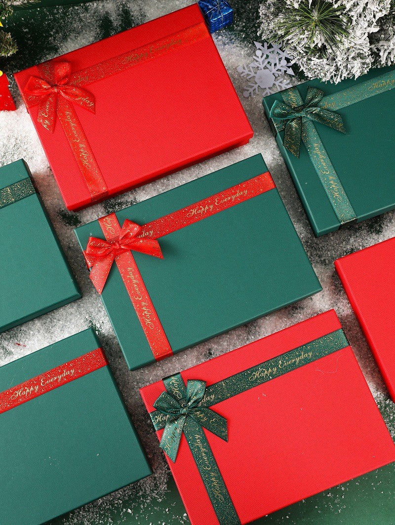 Suit set accessories gift boxes in red and green with decorative bows arranged on a snowy surface