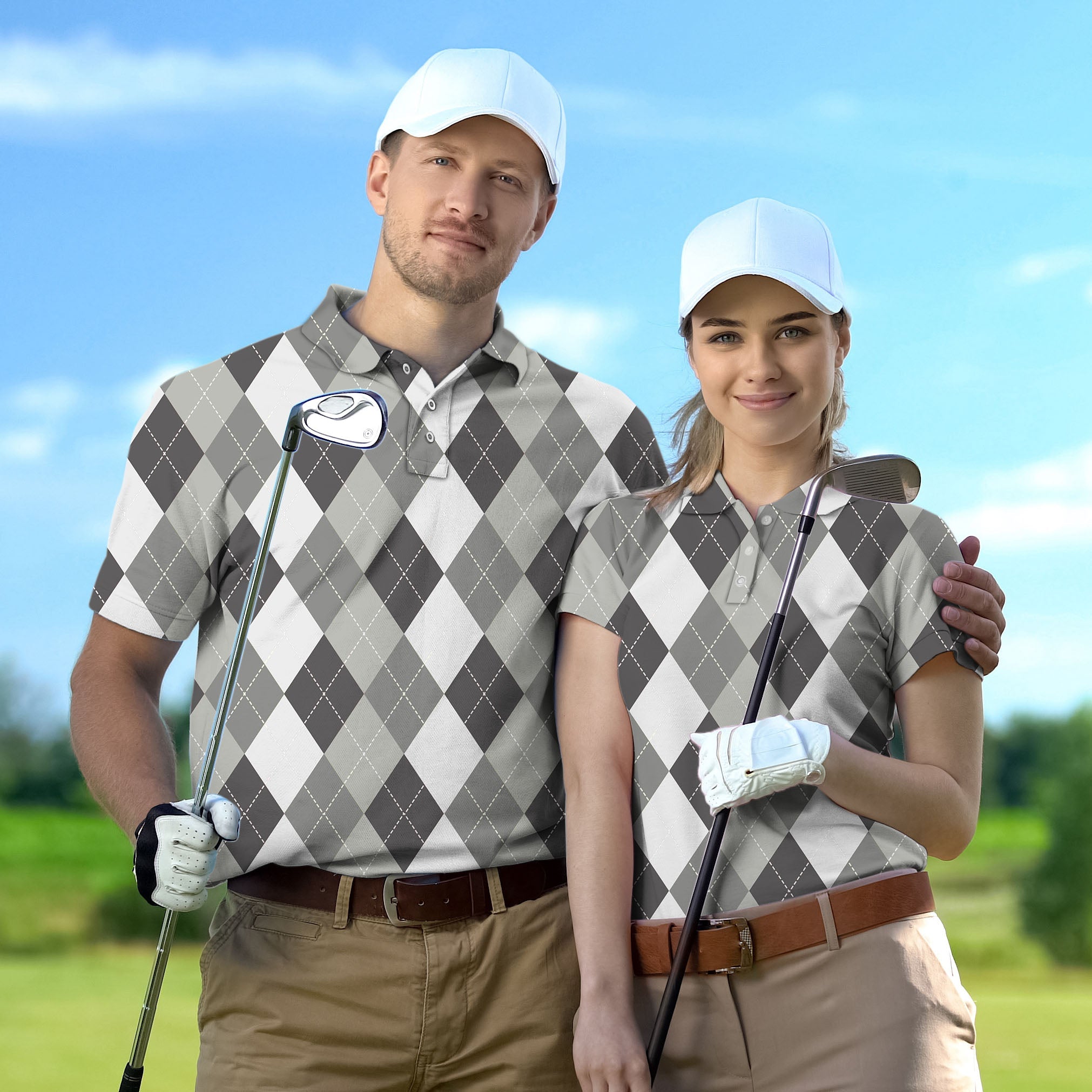Couple wearing grey Argyle set golf shirts with white caps on golf course holding clubs
