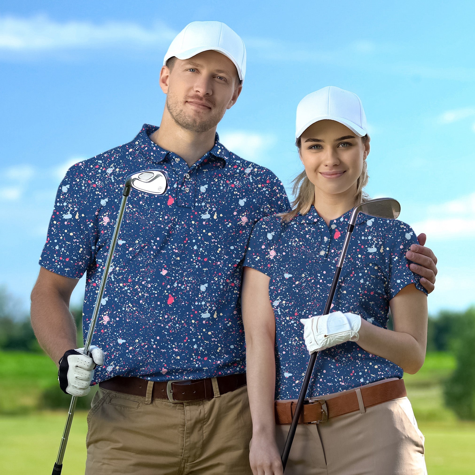 Couple wearing navy blue ink dots golf shirts holding clubs on course with white caps
