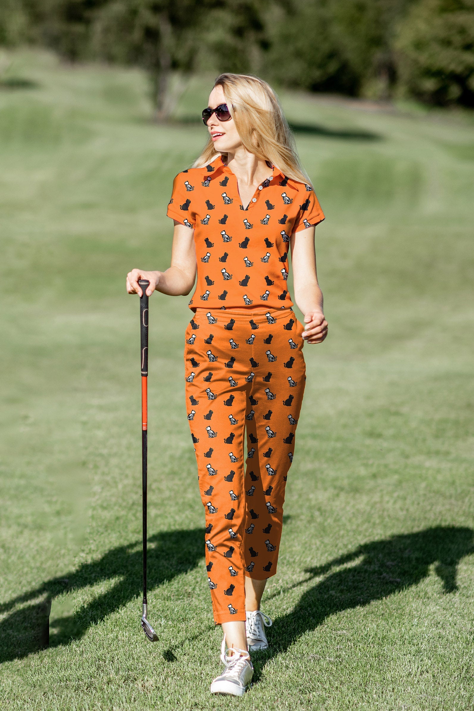 Women's Halloween skull cat golf polo and pants set in orange with stretch, moisture-wicking, UPF 40+ fabric