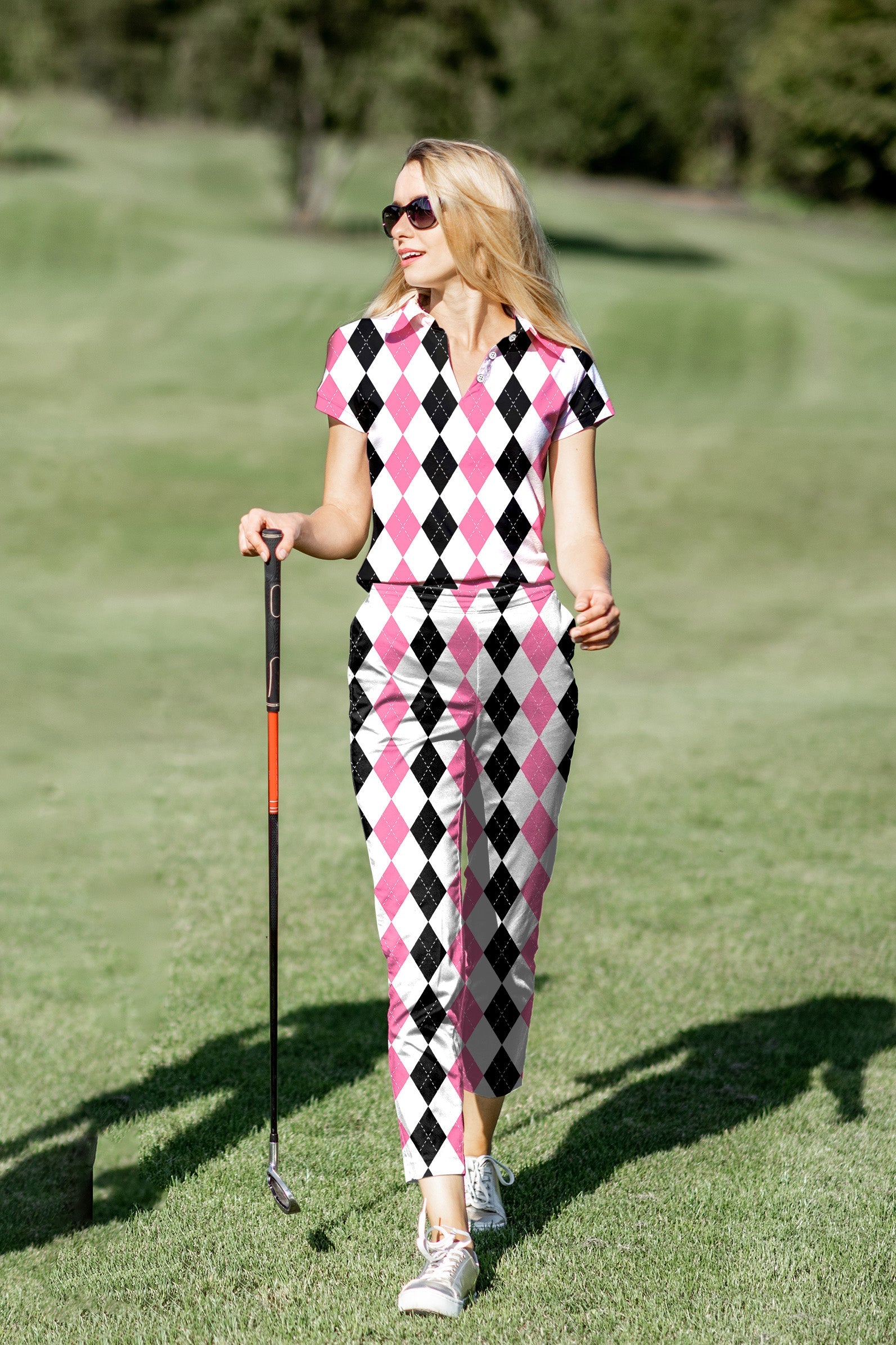 Women's golf polo and pants set in pink and black argyle pattern on golf course