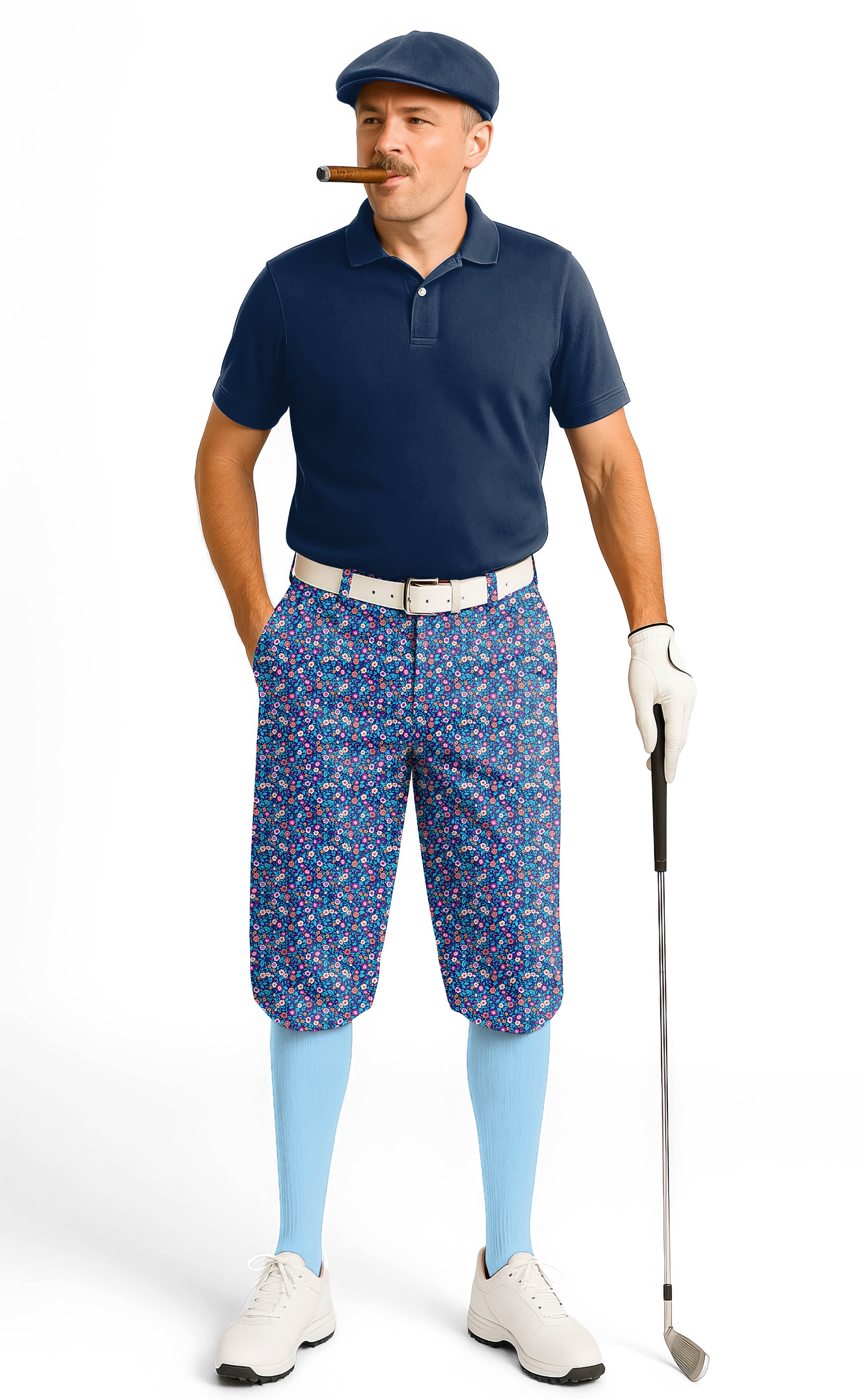 Man wearing dark floral men's golf knickers with ankle cuffs, navy polo, blue socks, white sneakers, and golf glove holding a golf club.