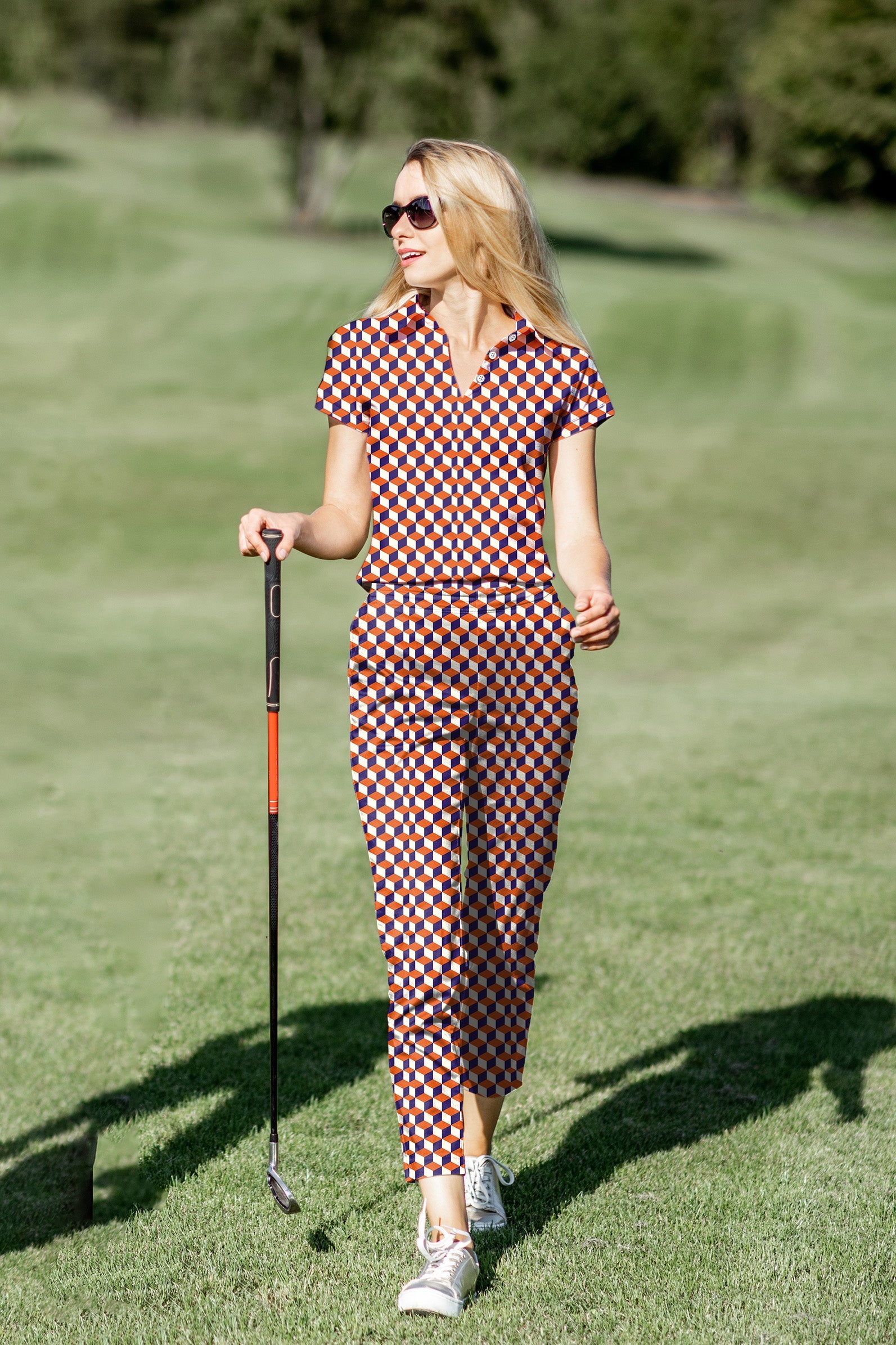 Women's golf polo and pants set in orange 3D square pattern with stretch, moisture-wicking fabric, and UPF 40+ protection