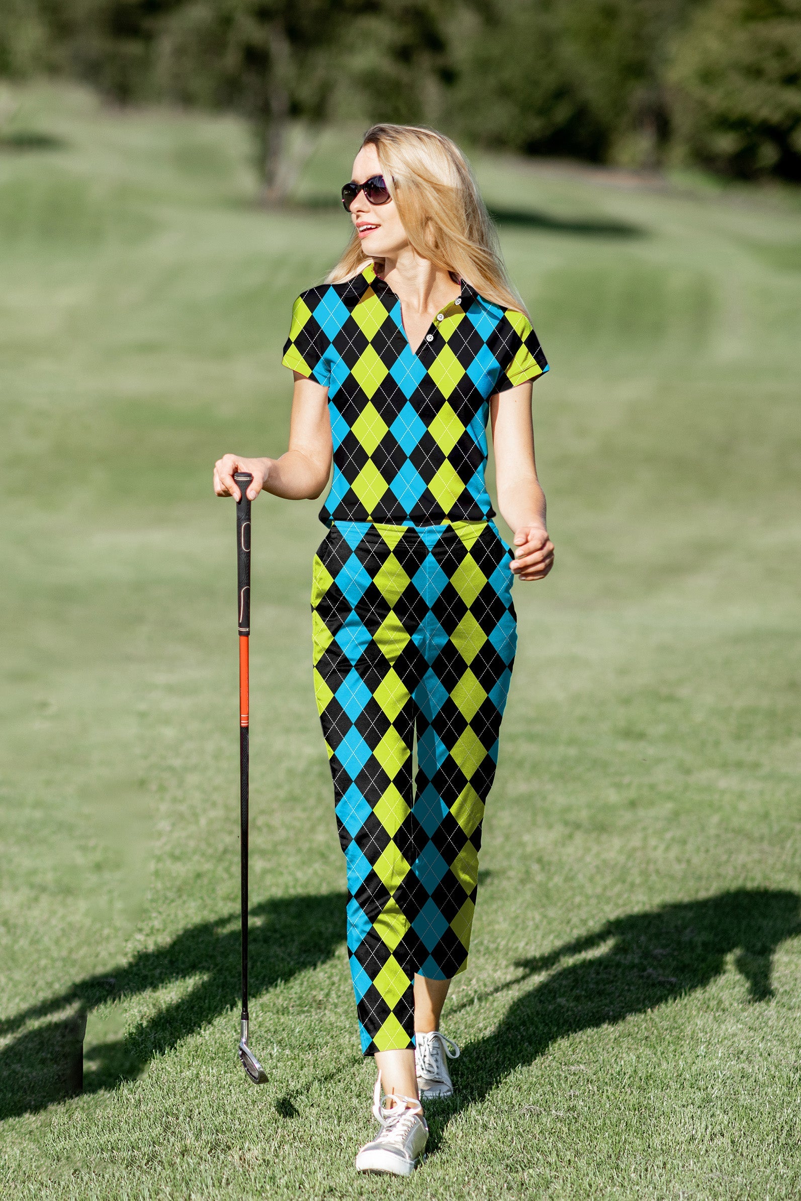 Women's golf polo and pants set with black, green, and blue argyle pattern on golf course
