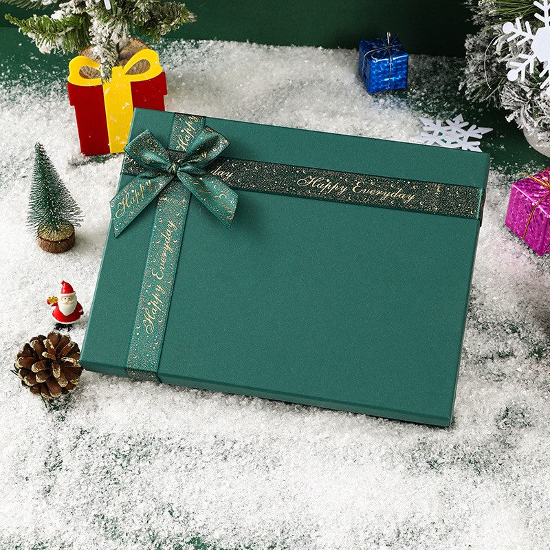 Green gift box with bow labeled Suit Set Accessories surrounded by festive decorations on snow background
