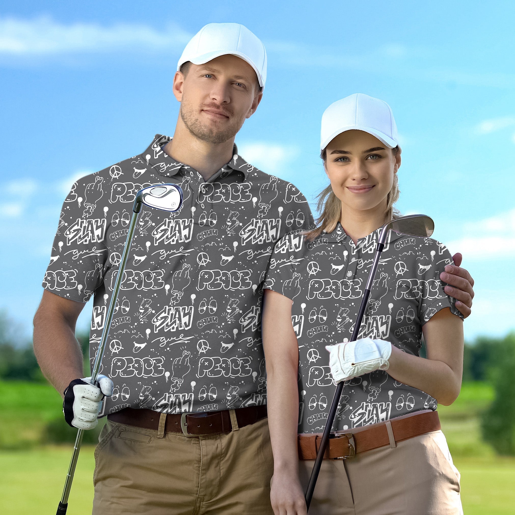Couple wearing gray Slay Peace golf shirts with white caps holding golf clubs on the course
