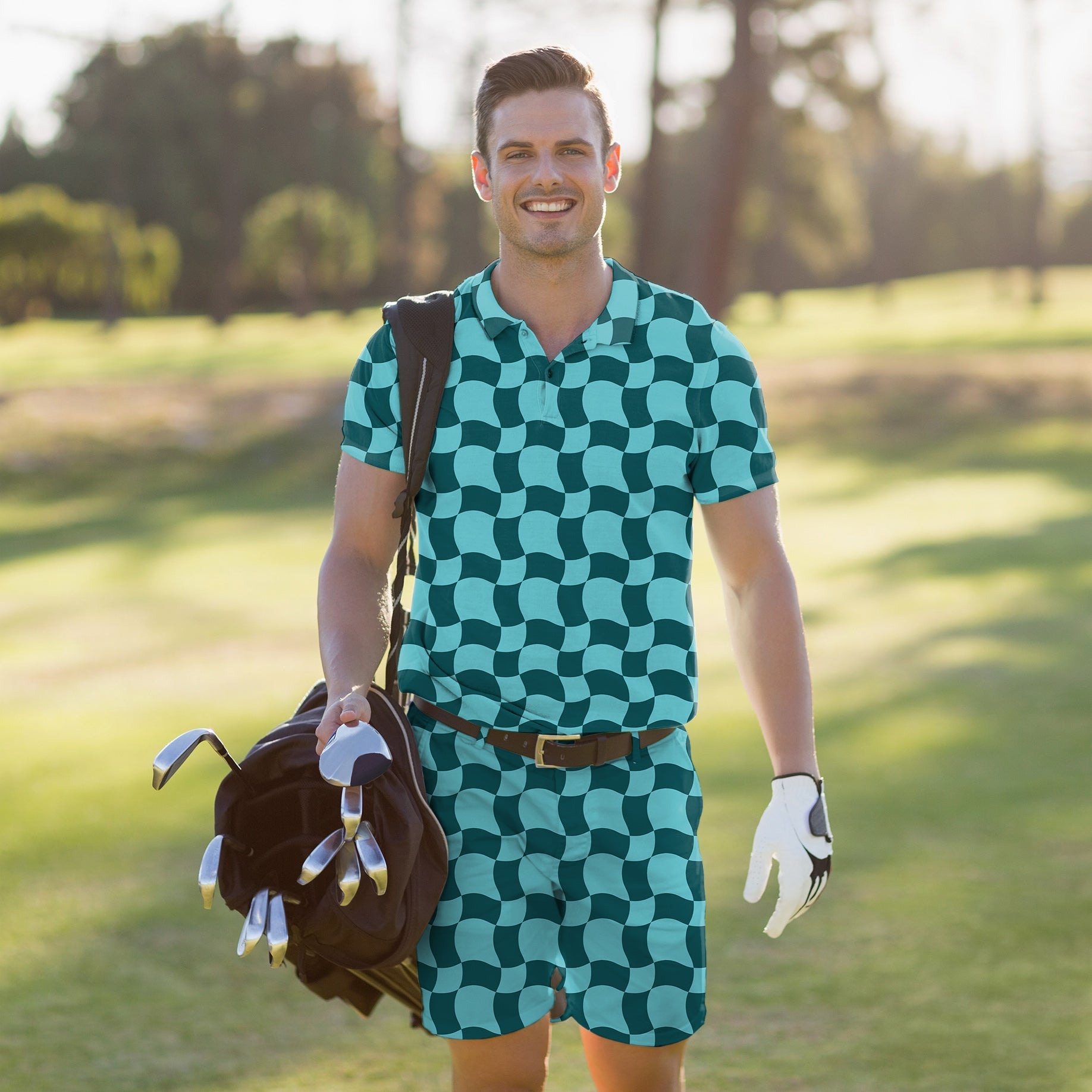Man wearing men's golf set polo and shorts with wavy square pattern carrying golf bag on course