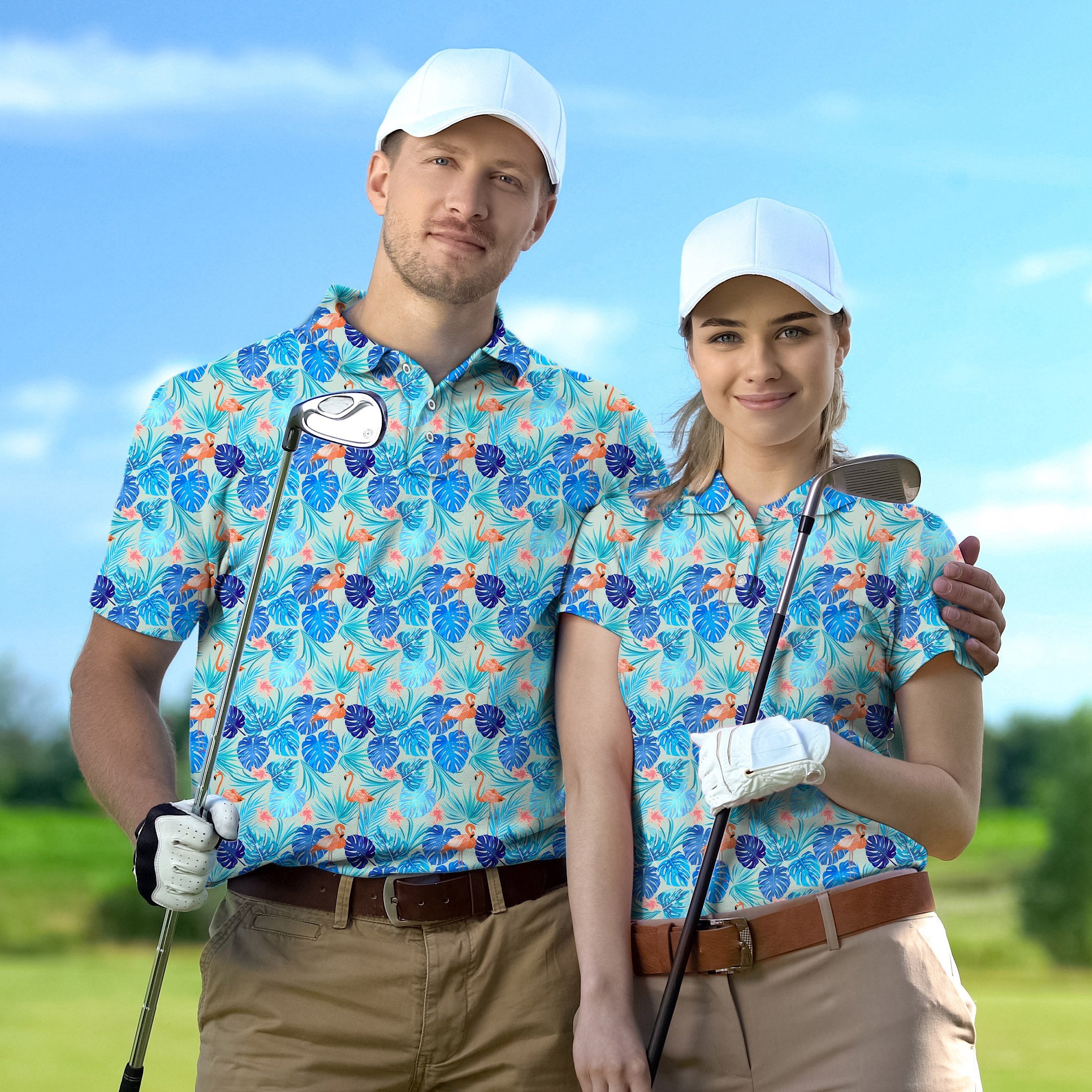 Couple wearing blue tropical flower print golf shirts with white caps holding golf clubs on course