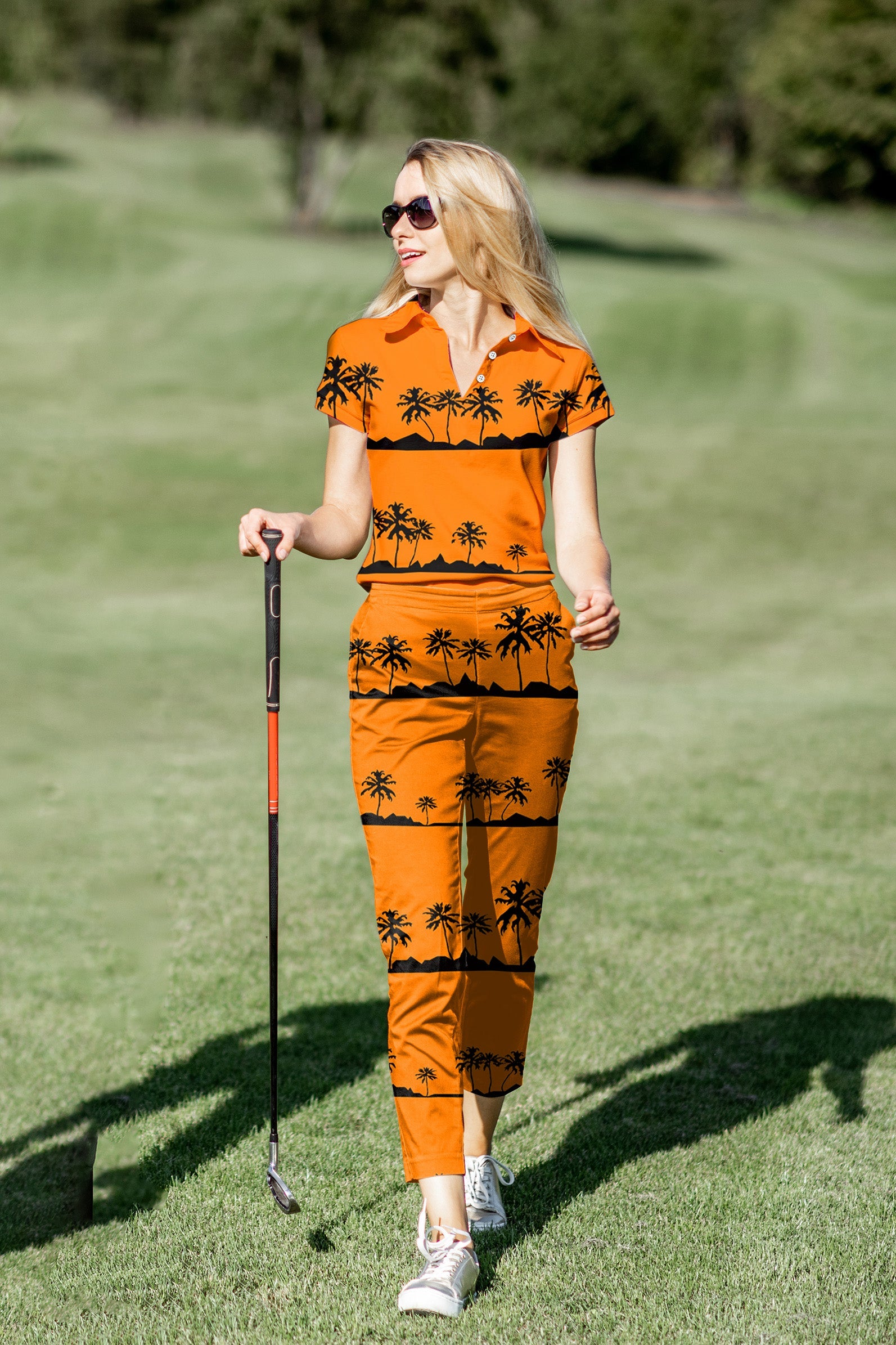 woman playing golf wearing orange palm tree print polo shirt and pants set on golf course