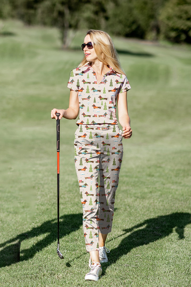 Woman wearing Christmas Dachshund women's golf polo and pants set on golf course with club