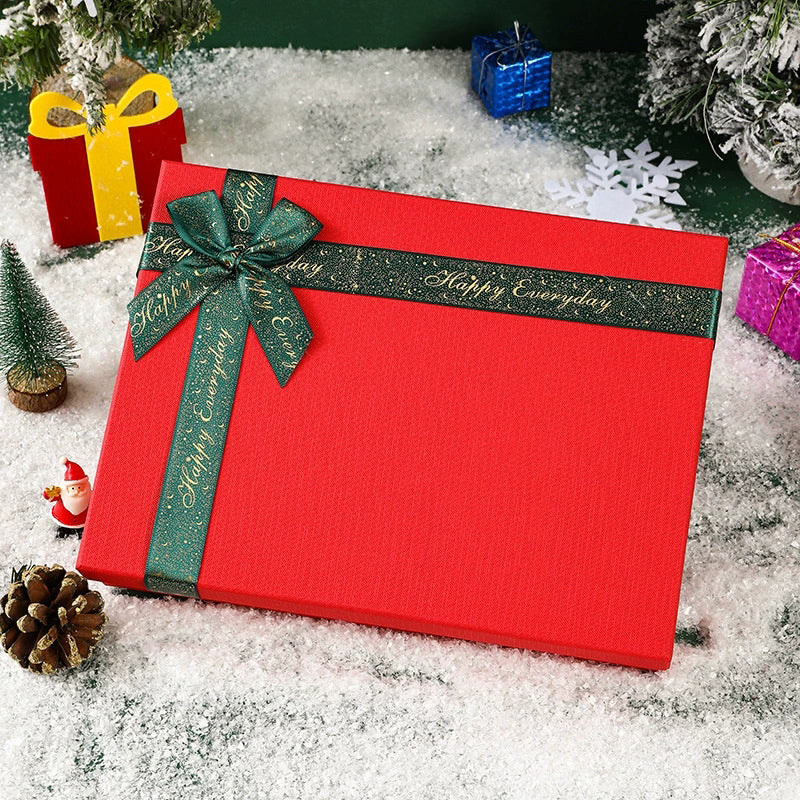 Red gift box with green ribbon for suit set accessories packaging in snowy holiday setting