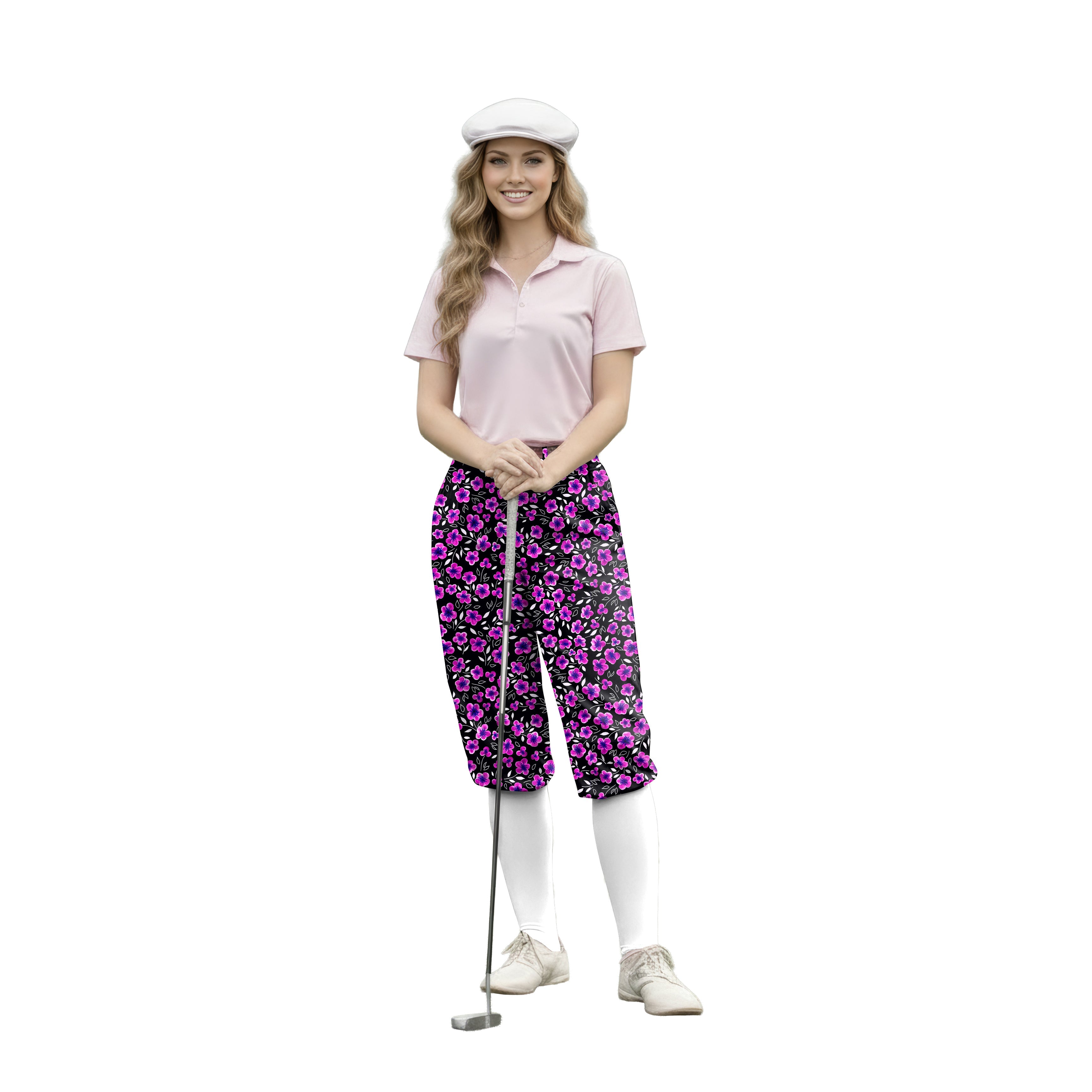Woman wearing Floral Out Womens Golf Knickers with pink floral pattern, light pink polo, white knee-high socks, and golf cap holding a putter.