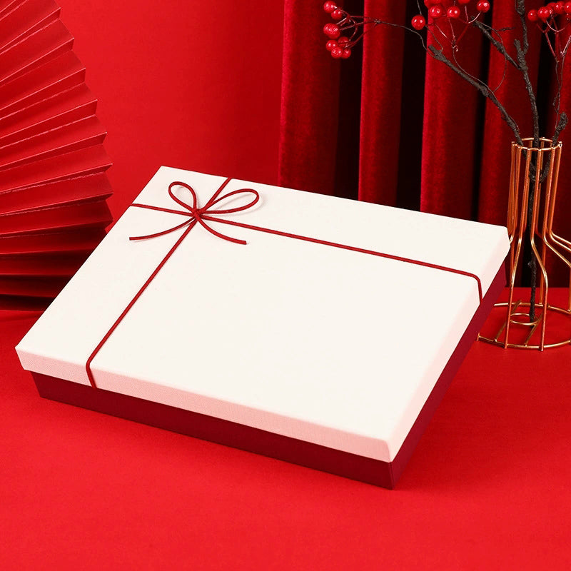 Elegant white gift box with red ribbon containing suit set accessories on red background